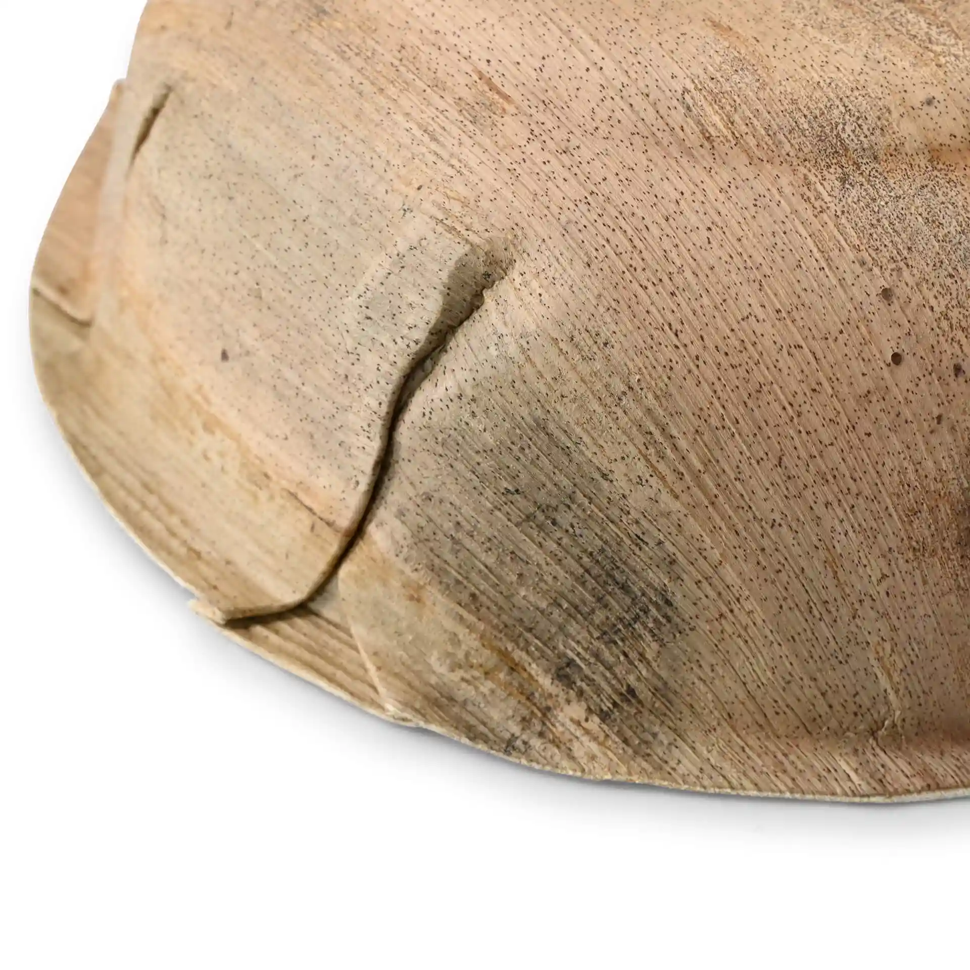 Close-up of a round palm leaf bowl with a grain texture and visible seams on the surface.