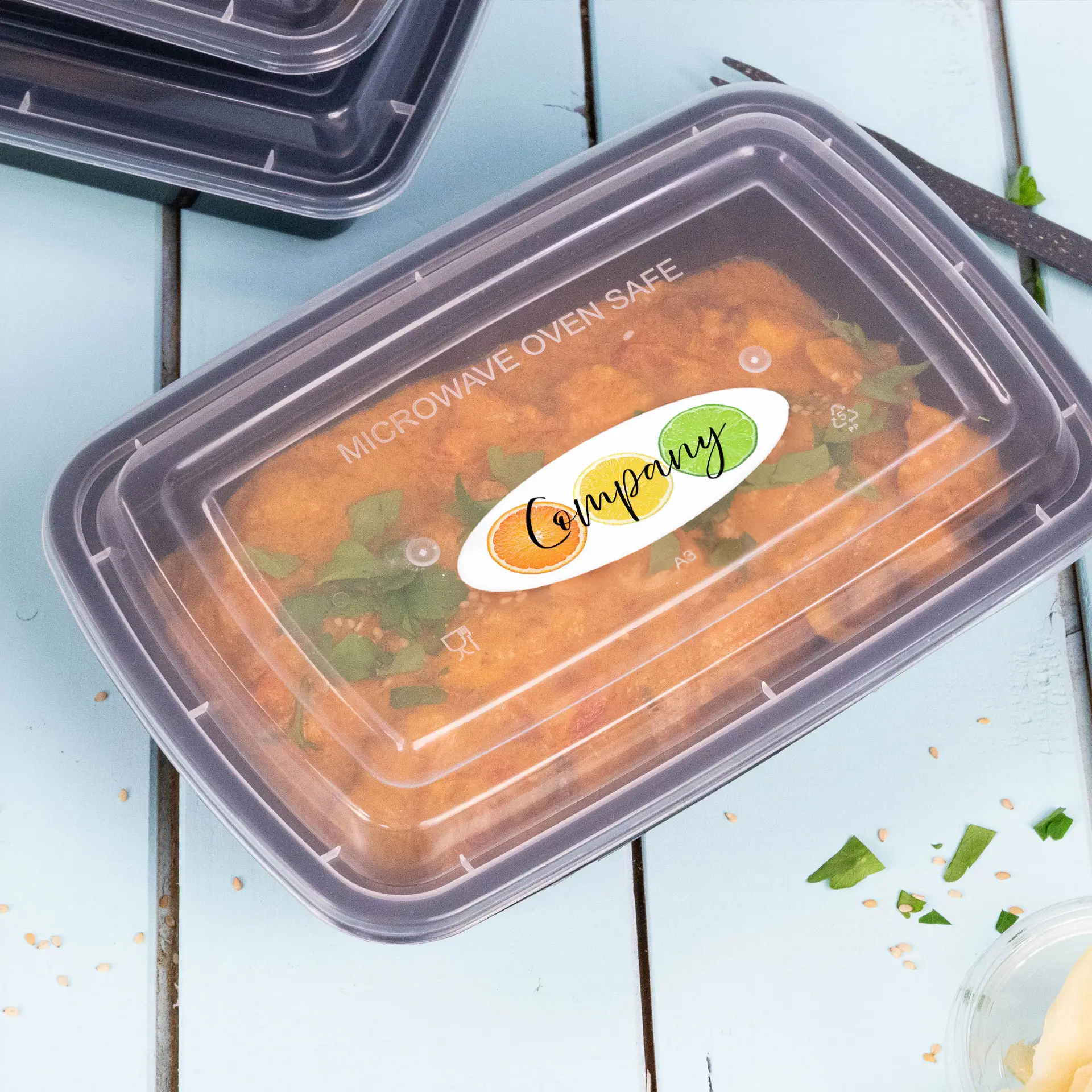 Transparent microwave-safe container with a custom printed label, filled with food and garnished with herbs, on a blue surface.