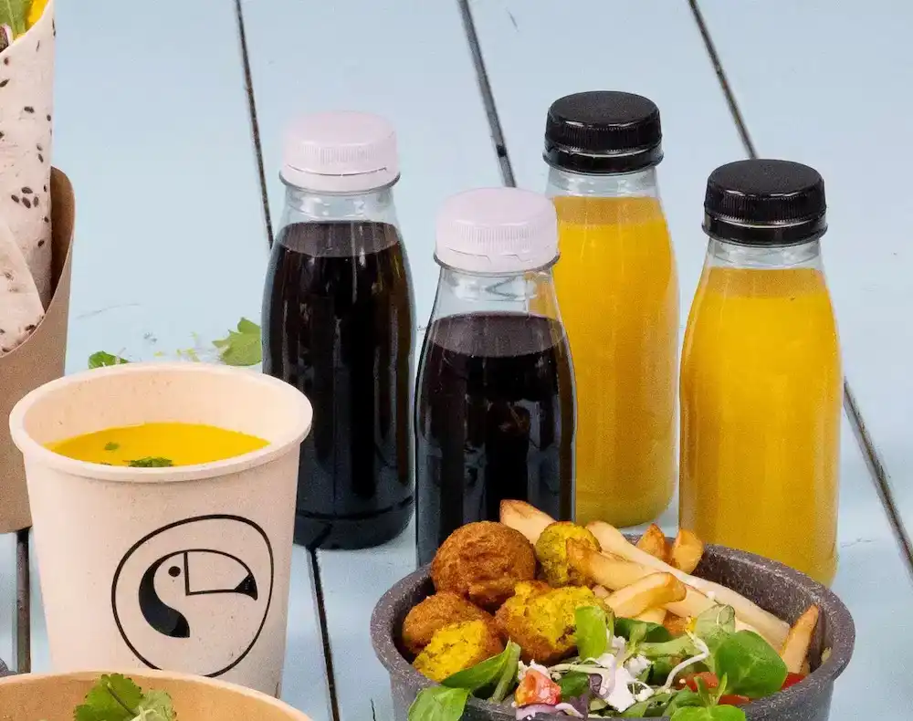 Assorted food items including rPET plastic bottles with various beverages, a cup of soup, and a bowl of salad, fries, and falafel.