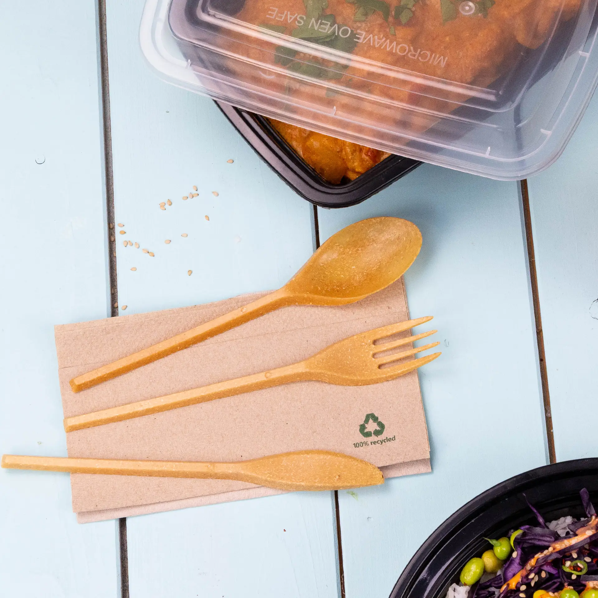 One reusable caramel knife made from bio-compound, placed next to a reusable fork and spoon on a brown napkin.