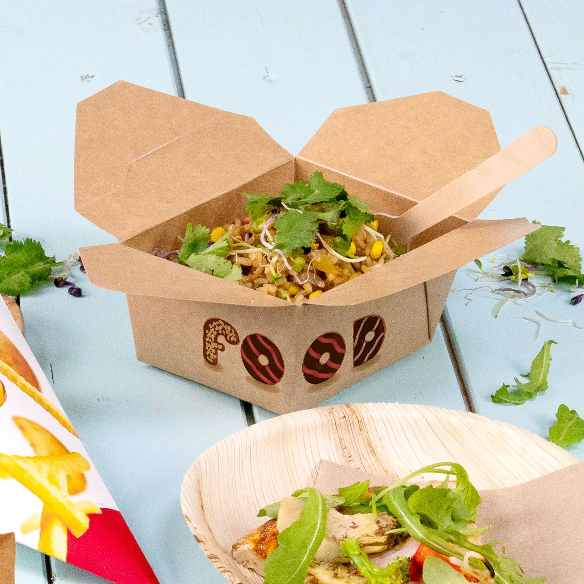 Custom printed takeaway box with food, featuring a design element; surrounded by greens and other food items on a light blue surface.