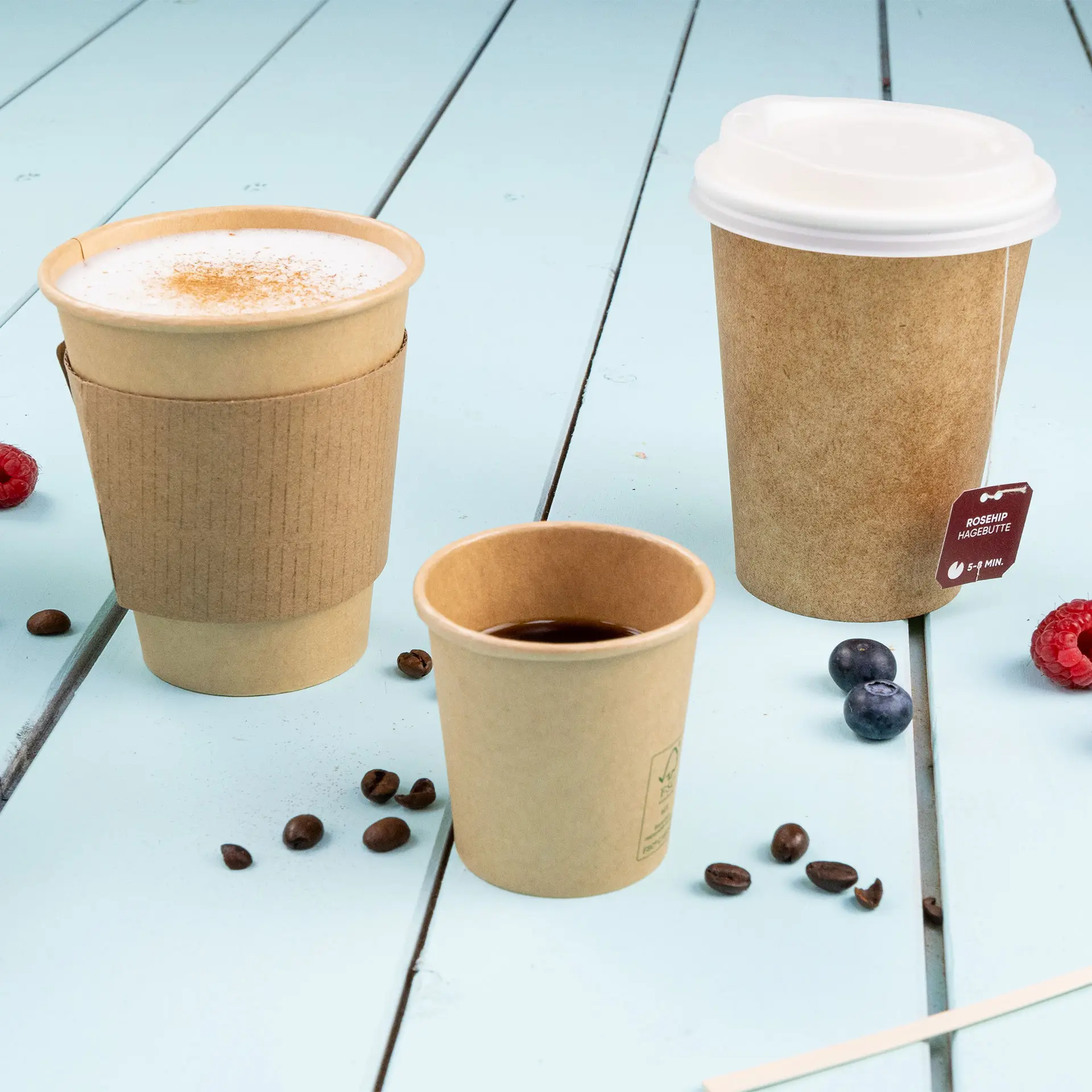 Image of three brown paper cups on a blue wooden surface, including a larger cup with a sleeve, a medium cup, and a small cup.
