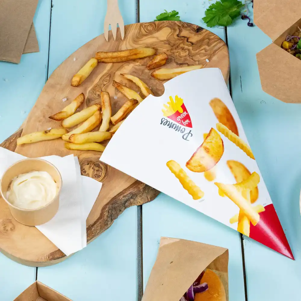 Tray with French fries in a cone, a small cup of dipping sauce, and additional fries on a wooden board.
