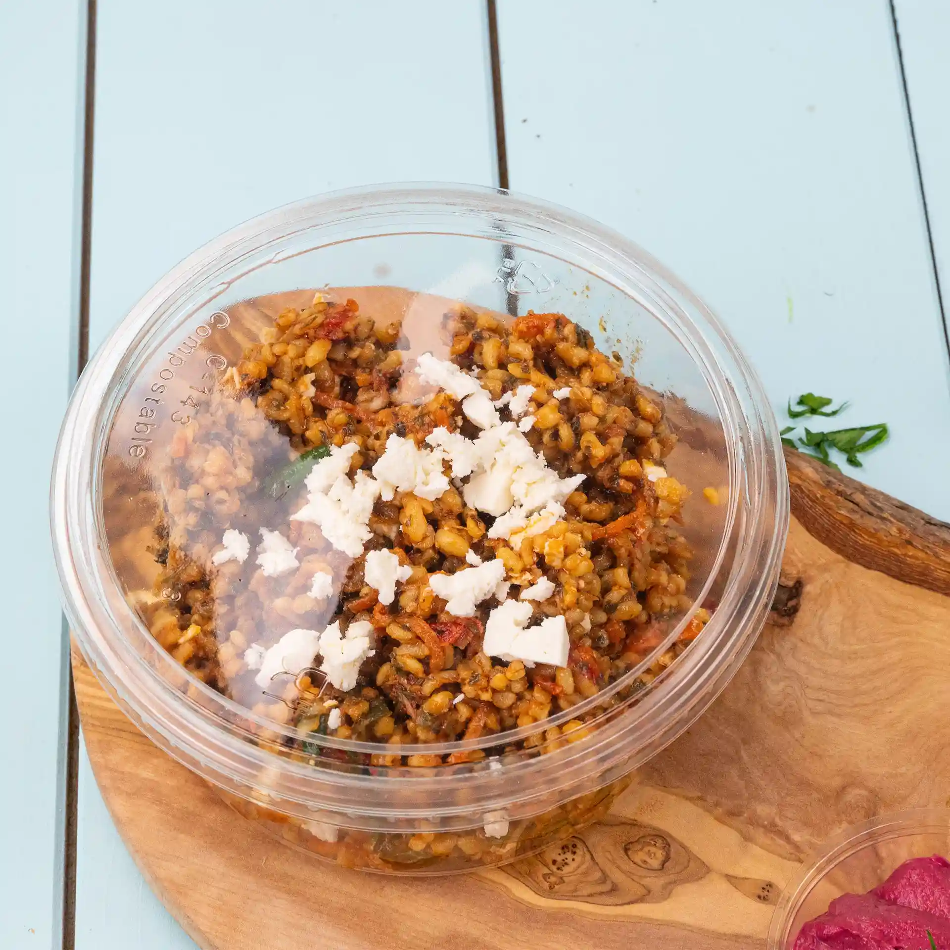 Transparent round deli cup lid with a clear view of the contents, featuring grains and crumbled cheese on top.