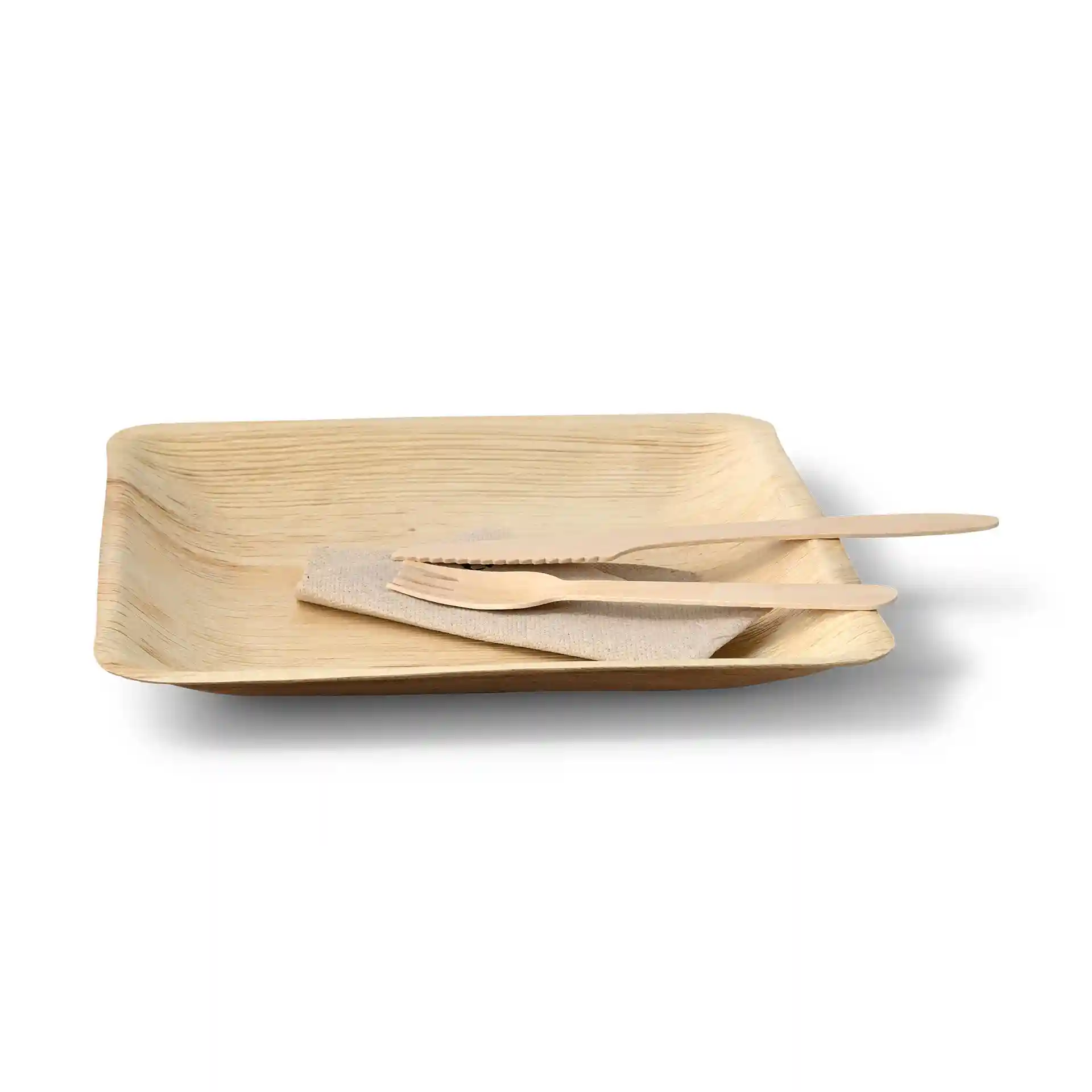 Square palm leaf plate with a grain texture, accompanied by a cloth napkin and wooden utensils.