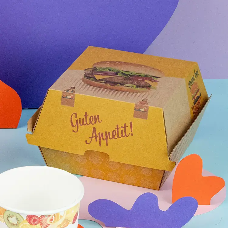 Brown and white burger boxes with "BURGER" text, a sesame seed bun burger, and French fries on a wooden surface.