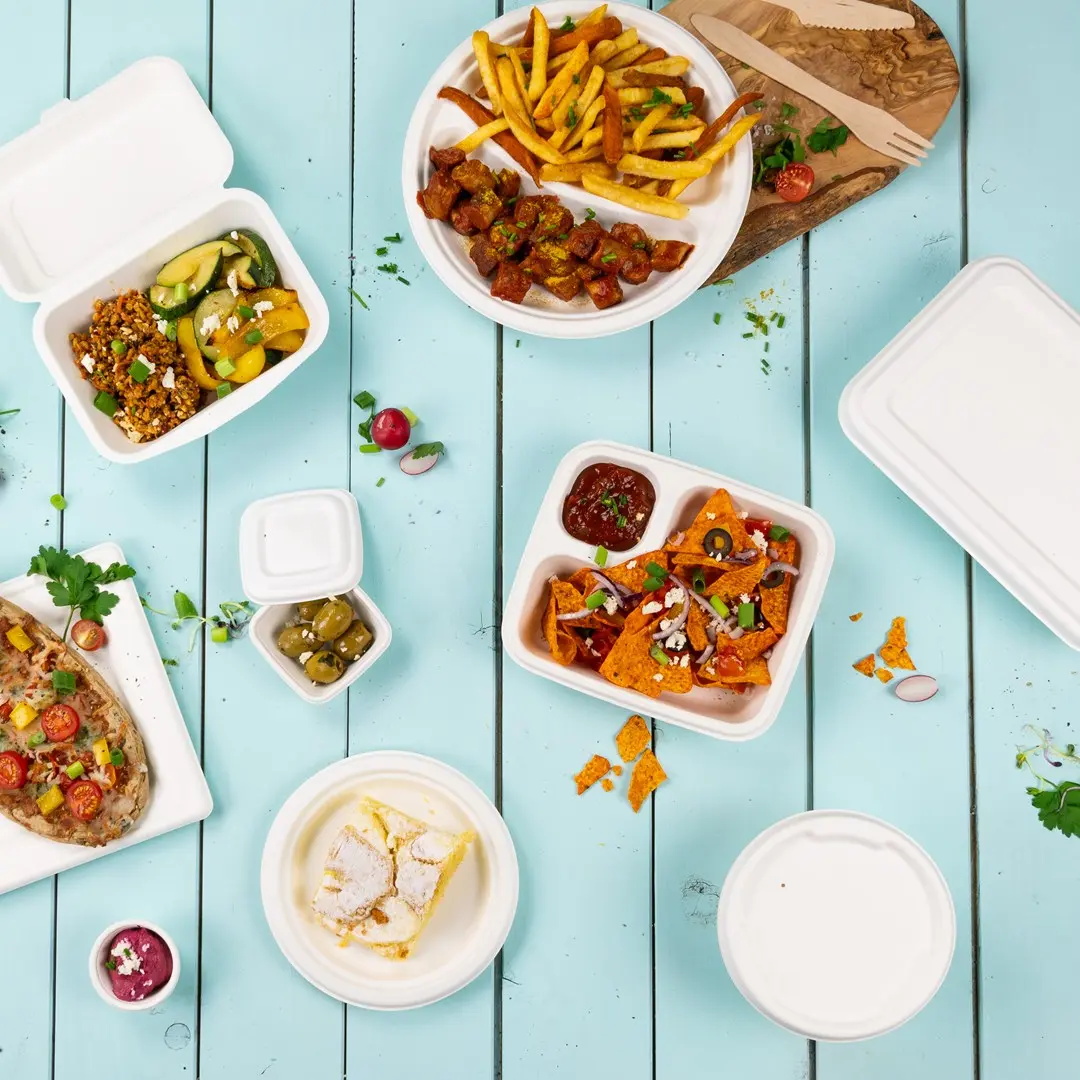 Assorted food items in takeout containers on a blue wooden surface, including fries, nachos, and a dessert.