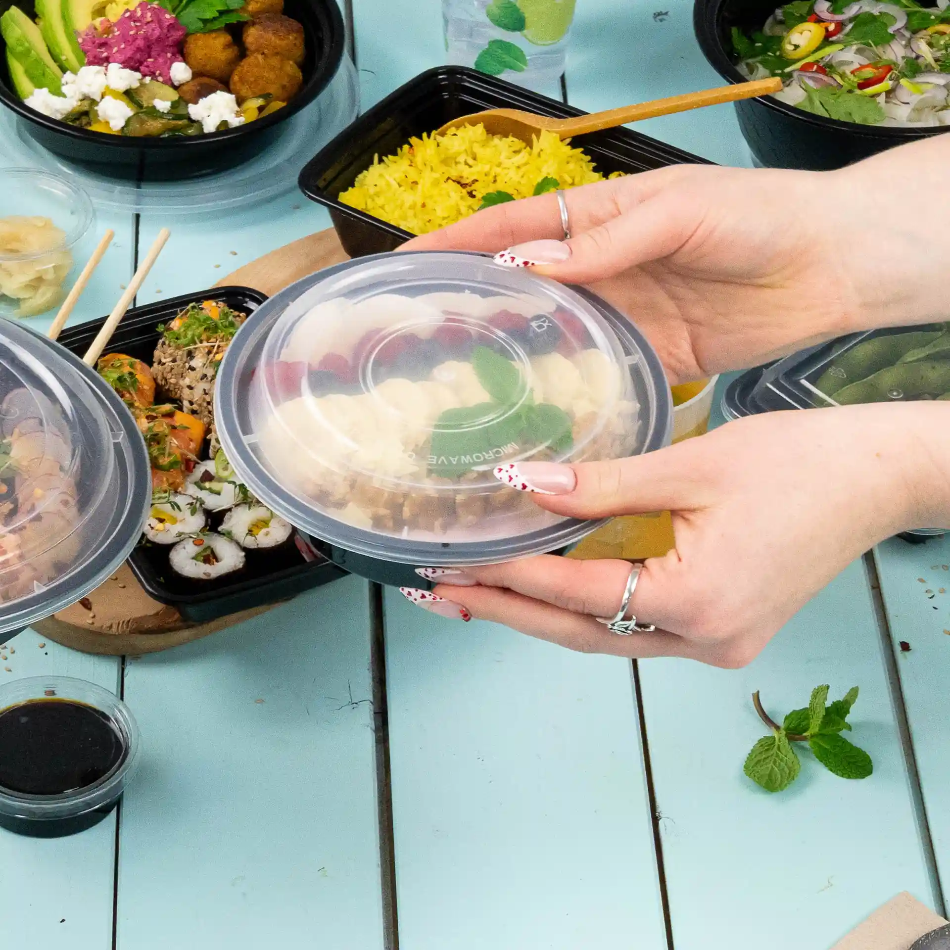 Transparent round reusable lid made of PP, held above a table with various food containers.