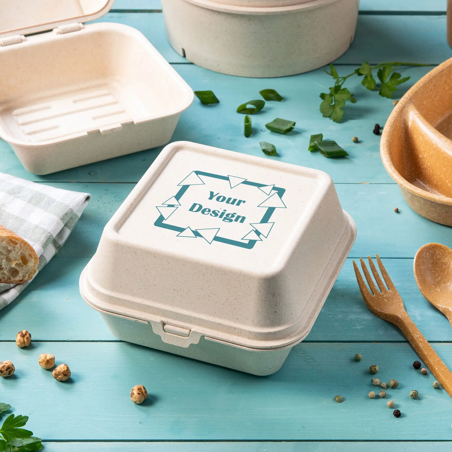 Reusable burger box made from wood bio-compound, featuring a customizable lid, placed among food items and utensils.