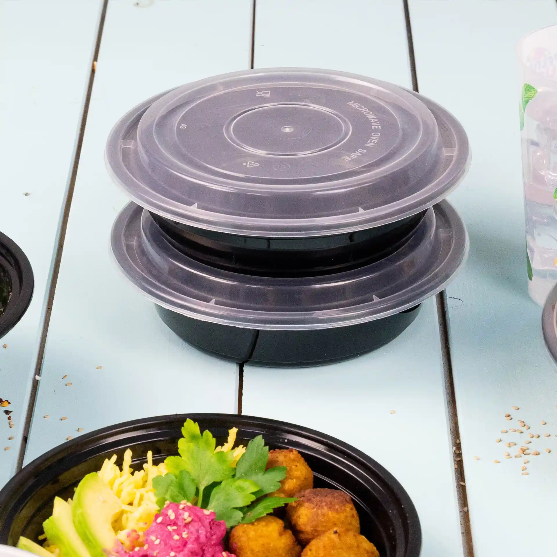 Stacked round containers with transparent lids, made of PP, on a blue surface.