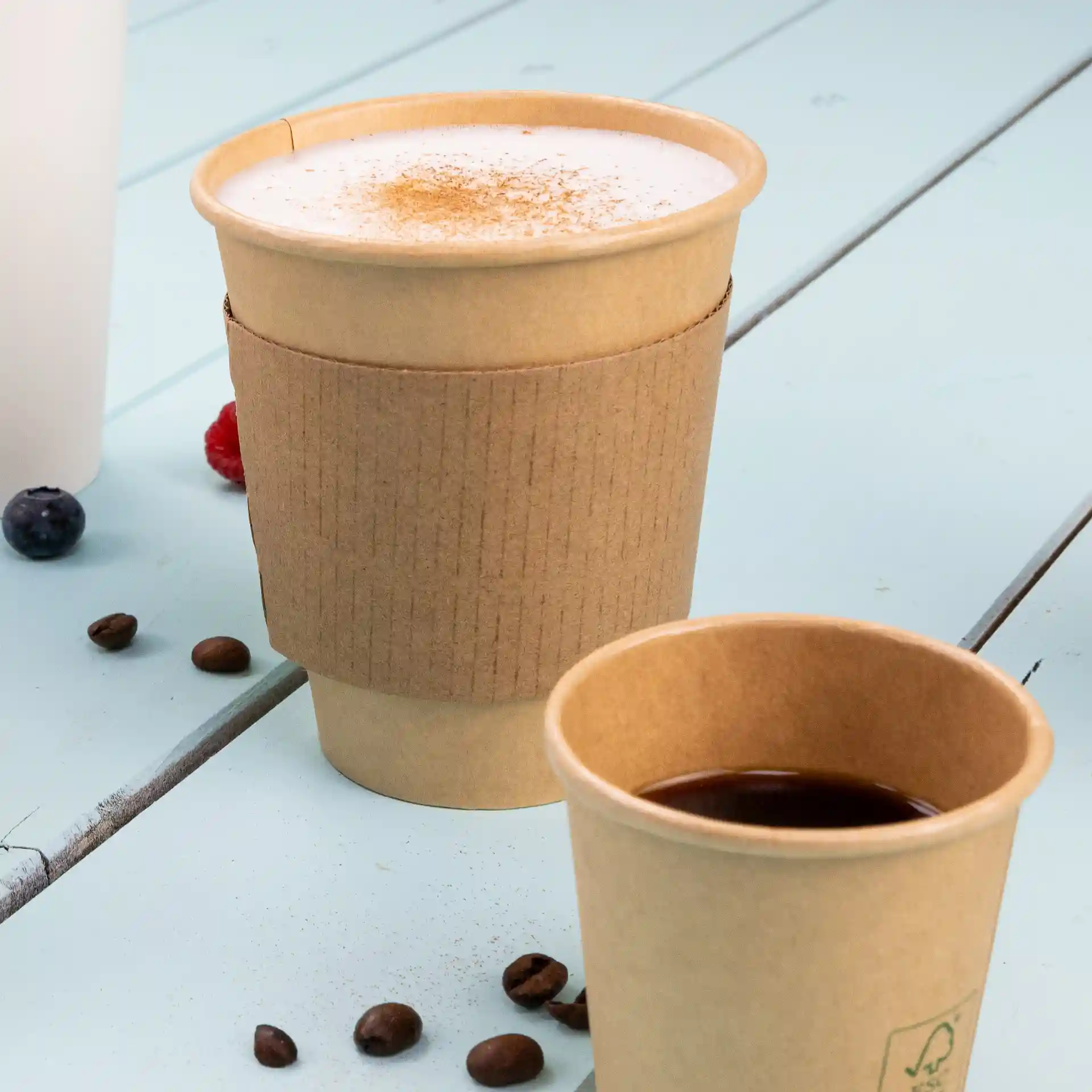 Brown single wall paper cup with a PLA coating, 300 ml capacity, placed next to a smaller cup on a blue surface.