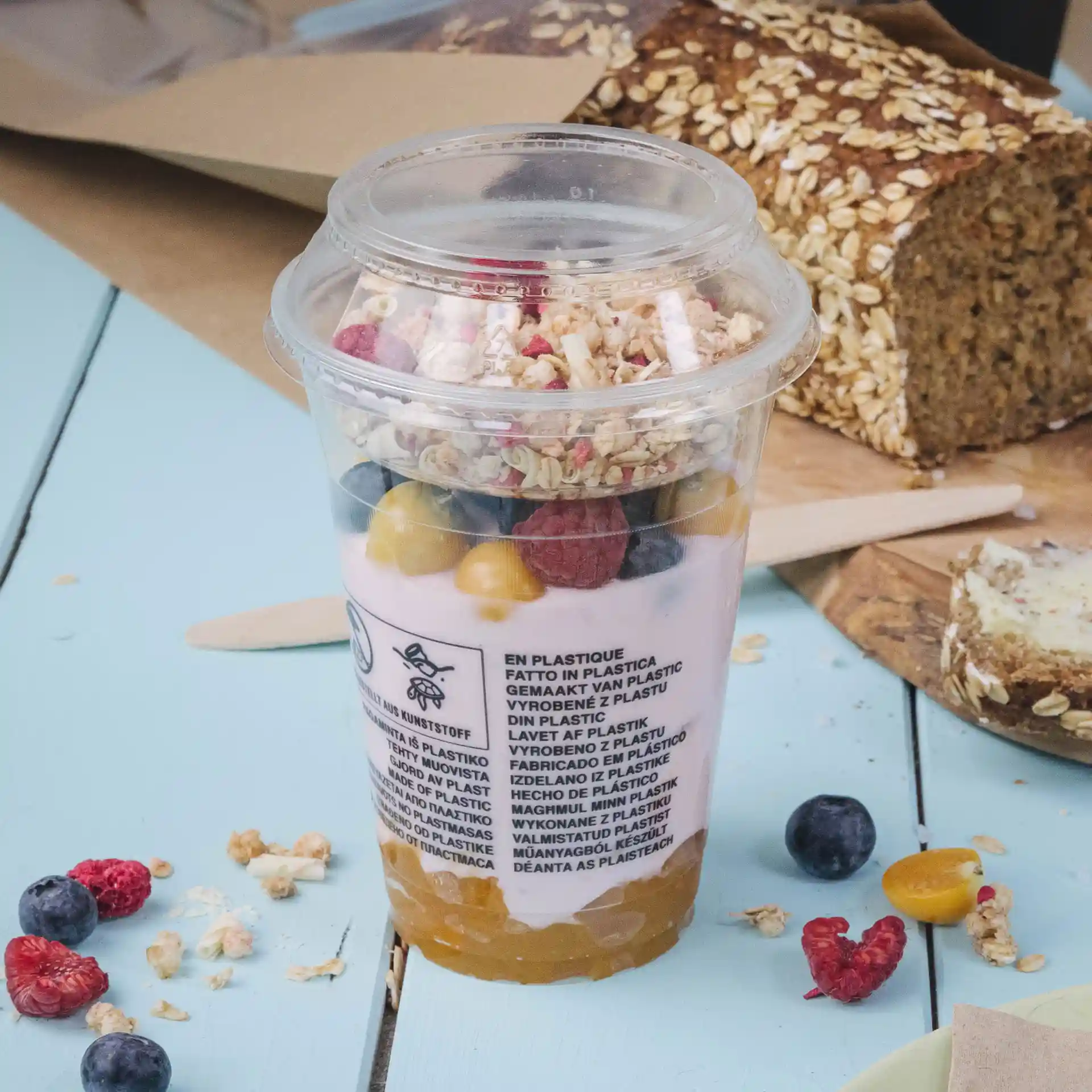 Clear plastic cup filled with yogurt, granola, and mixed fruits, with a diameter of 95 mm.