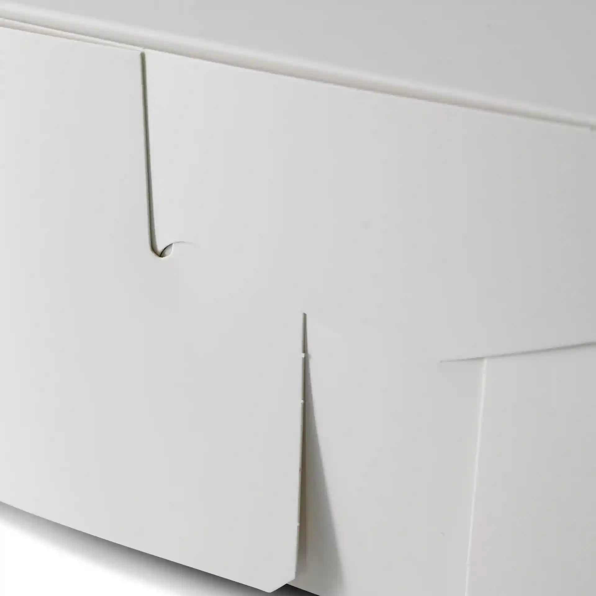 Close-up of a white cake box with a folded flap, showing the edge and corner details.